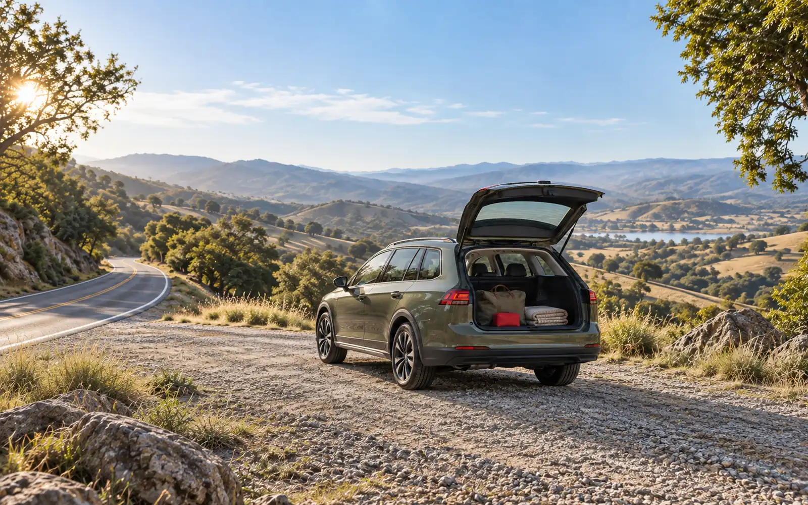 An unbadged compact wagon parked at a roadside pull-off with its hatch open and travel bags inside, ready for a road trip